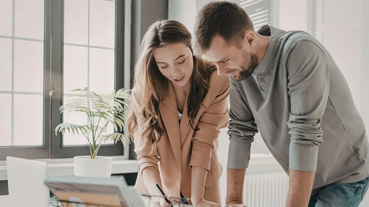 Two colleagues reviewing documents and a laptop